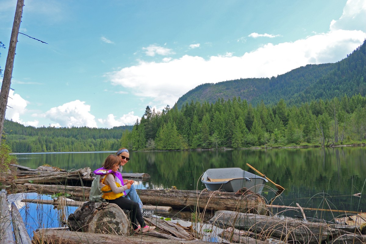 Kathleen Duborg and Bronny sit on the logs at Klein Lake